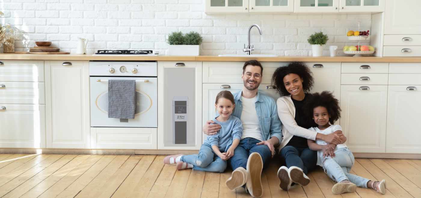 Weiches Trinkwasser aus der Leitung für die ganze Familie Vierköpfige Familie sitzt zufrieden in ihrer Küche mit eingebauter Osmoseanlage und 3-Wege-Wasserhahn