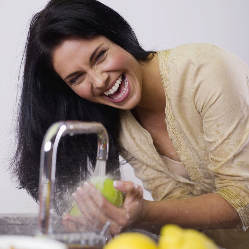 Symbolbild Frau wäscht Obst am Wasserhahn